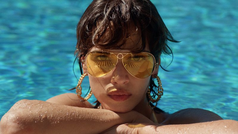 Modella in piscina con occhiali aviator Dolce&Gabbana x Ray-Ban a lenti gialle