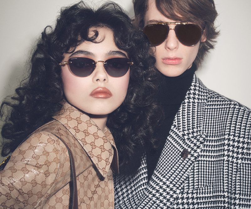 Coppia con occhiali da sole Gucci e cappotti con monogramma e pied-de-poule