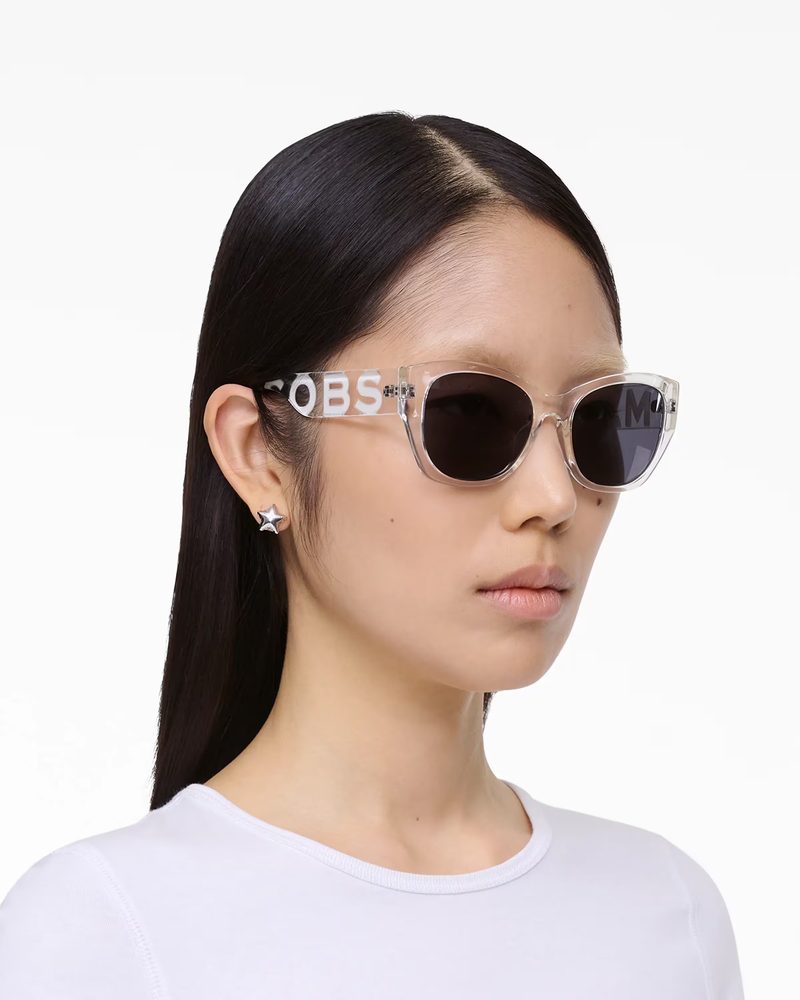 Modella con occhiali da sole Marc Jacobs trasparenti con logo sulle aste