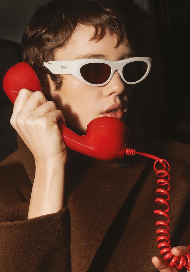 Modella con occhiali da sole cat-eye bianchi MAX&Co. e telefono rosso