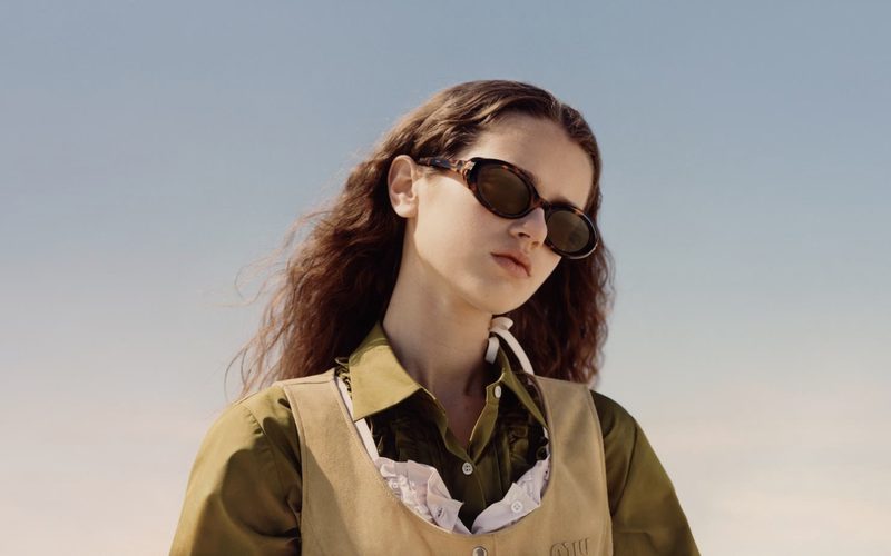 Donna con occhiali da sole Miu Miu ovali marroni all'aperto