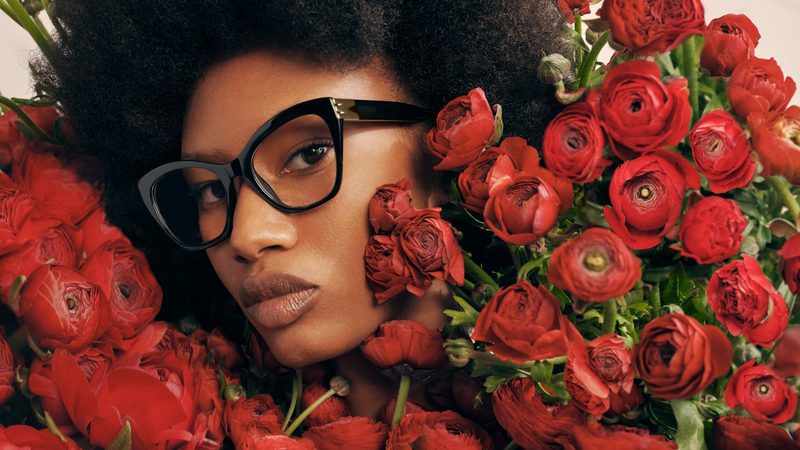 Donna con occhiali da vista Moschino neri tra fiori rossi