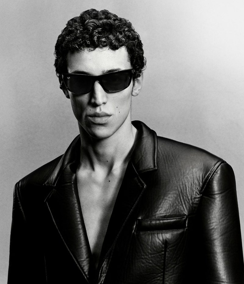 Uomo in bianco e nero con occhiali da sole Ray-Ban neri e giacca di pelle