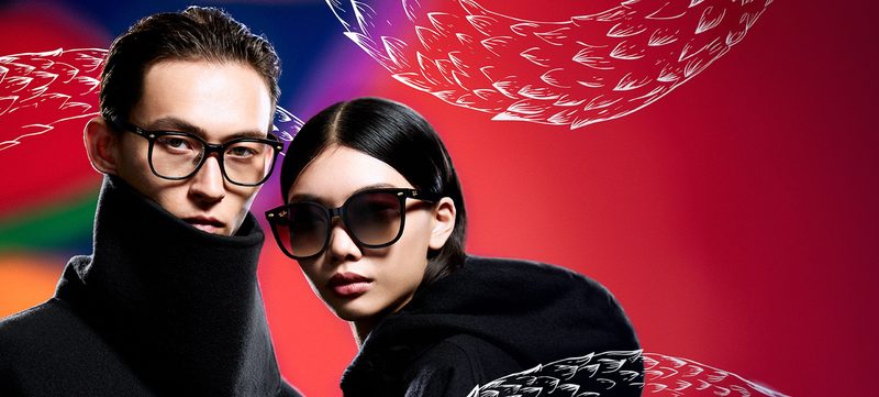 Uomo con occhiali da vista e donna con occhiali da sole Ray-Ban su fondo rosso