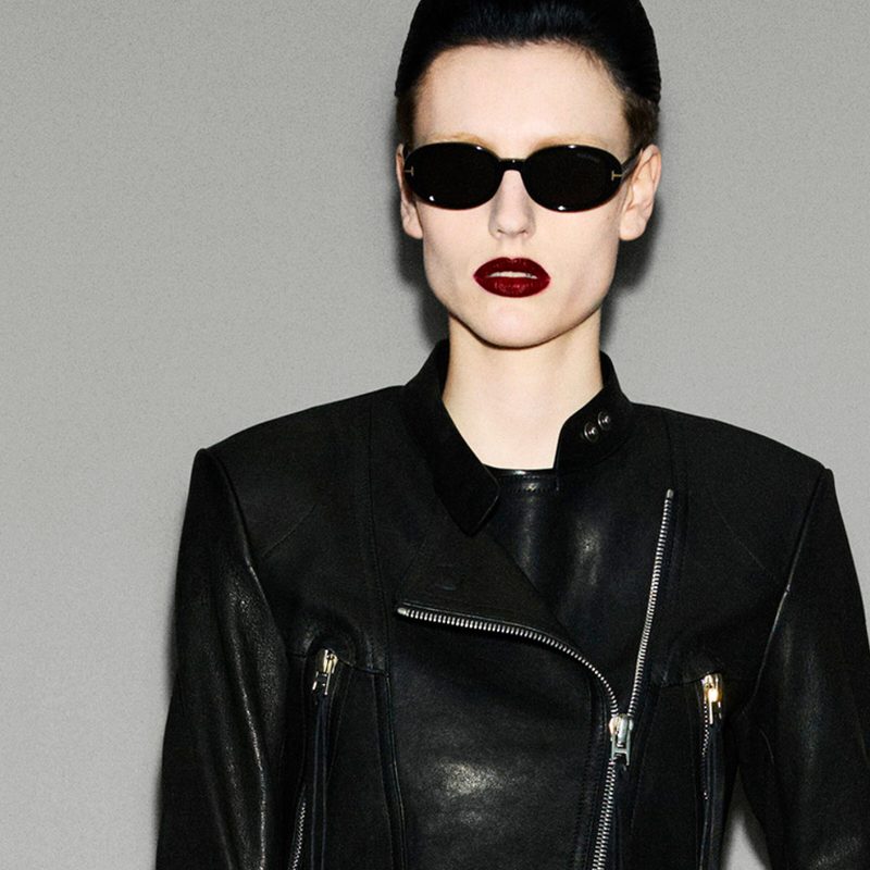 Donna con occhiali da sole Tom Ford ovali neri e giacca di pelle