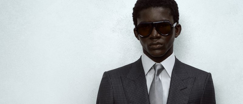 Uomo in abito grigio con occhiali da sole Tom Ford a lenti marroni