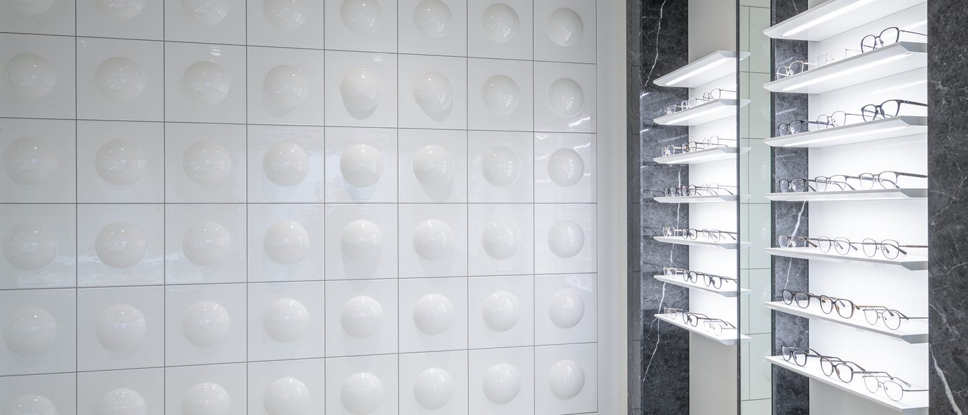 La parete di ceramica a cupole e le mensole illuminate con le montature da vista